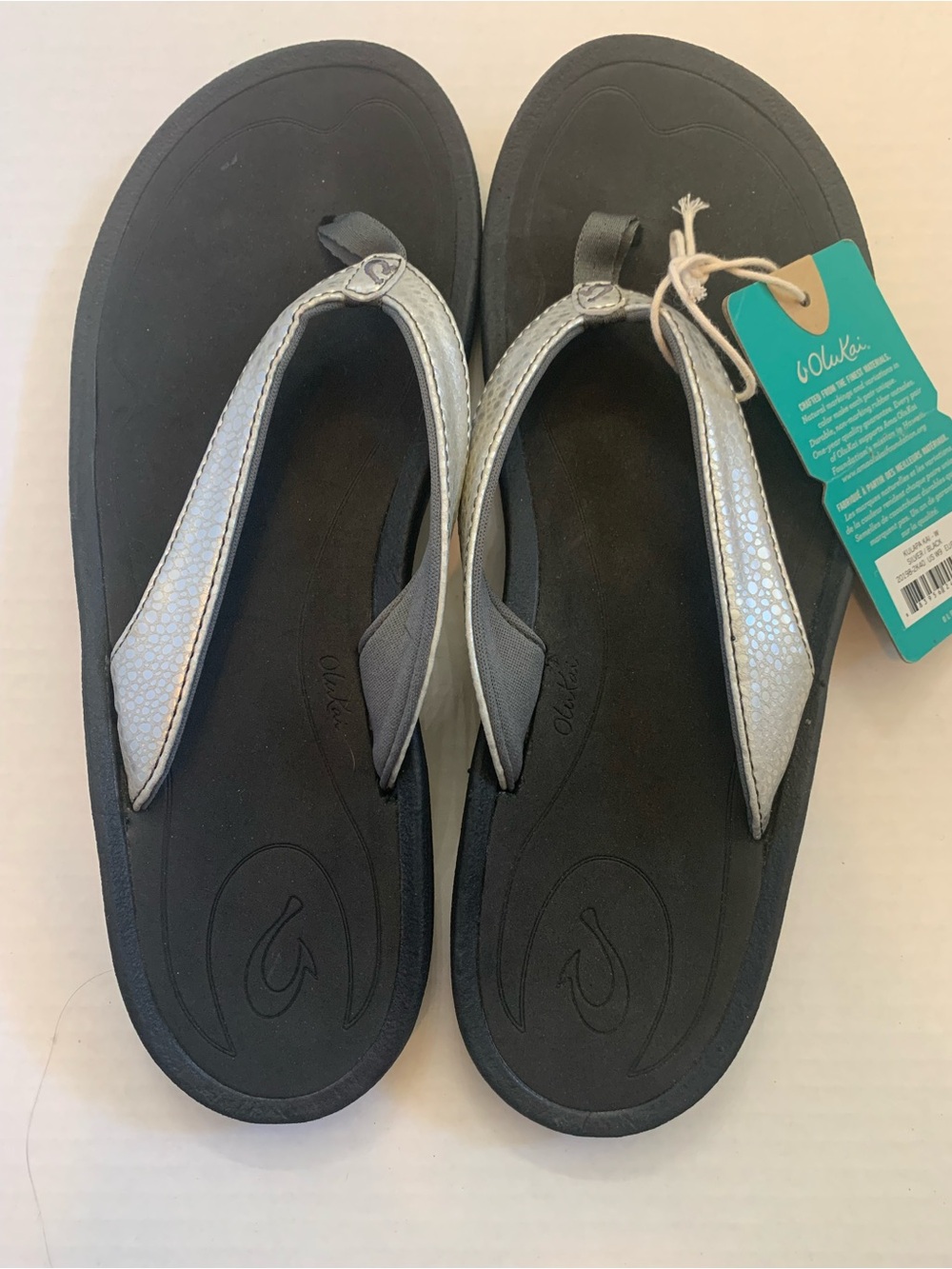 OluKai Women’s Silver Metallic Strap Black Footbed Flip Flops